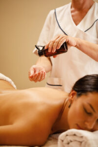 unrecognizable therapist pouring oil her hands before massage treatment wellness center scaled.jpg